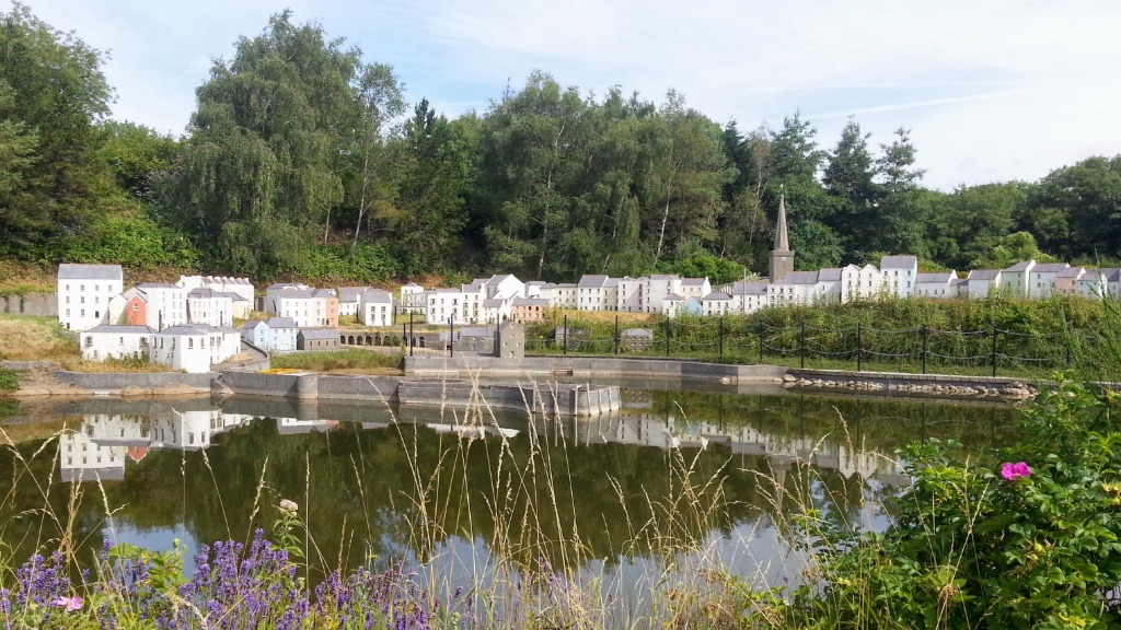Panoramic view across the miniature harbor lake toward the town walls, terraced streets, and St Mary's Church spire
